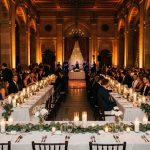 Elegant wedding reception hall with dramatic warm lighting and long tables.